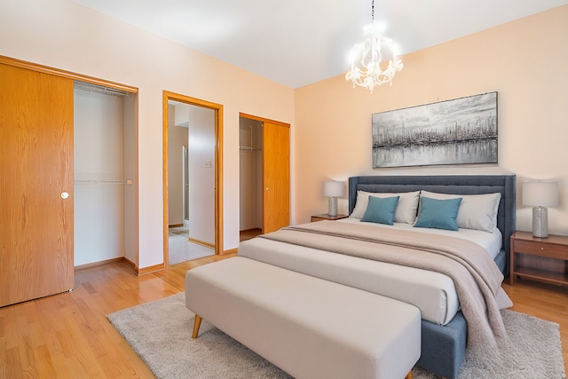 bedroom featuring two closets, wood finished floors, a chandelier, and baseboards