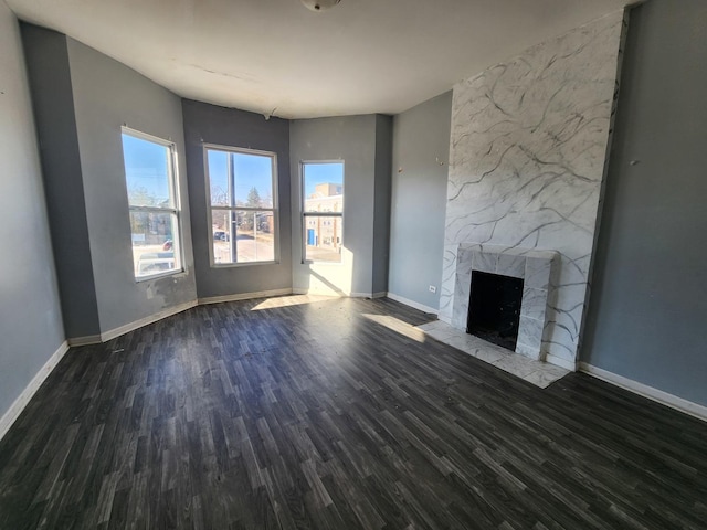 unfurnished living room with dark wood-type flooring, a fireplace, and baseboards