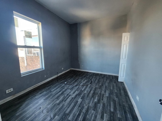 spare room with dark wood-type flooring and baseboards