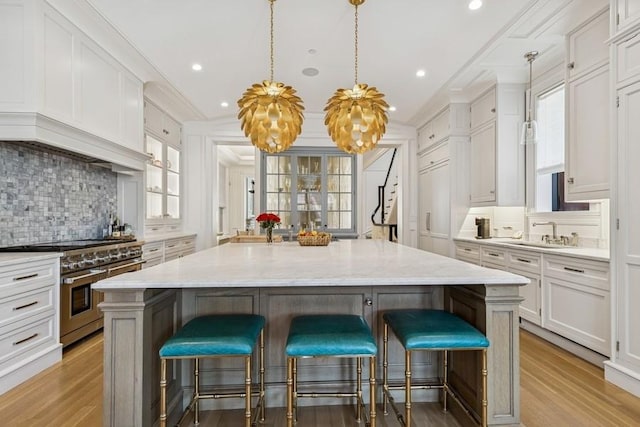 1855 N Hermitage Ave, Chicago, IL 60622 - kitchen with white cabinetry, double oven range, decorative backsplash, a center island, and light wood-style flooring