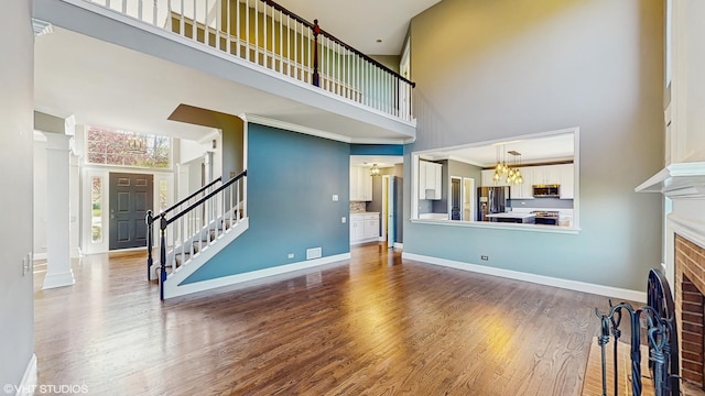 8 Georgetown Ct, Algonquin, IL 60102 - unfurnished living room featuring a high ceiling, a brick fireplace, wood finished floors, a chandelier, and stairs