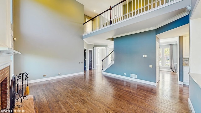 8 Georgetown Ct, Algonquin, IL 60102 - unfurnished living room with a brick fireplace, a towering ceiling, stairs, wood finished floors, and baseboards