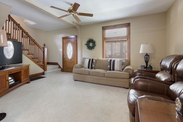 living room with light colored carpet, healthy amount of natural light, stairway, and a ceiling fan