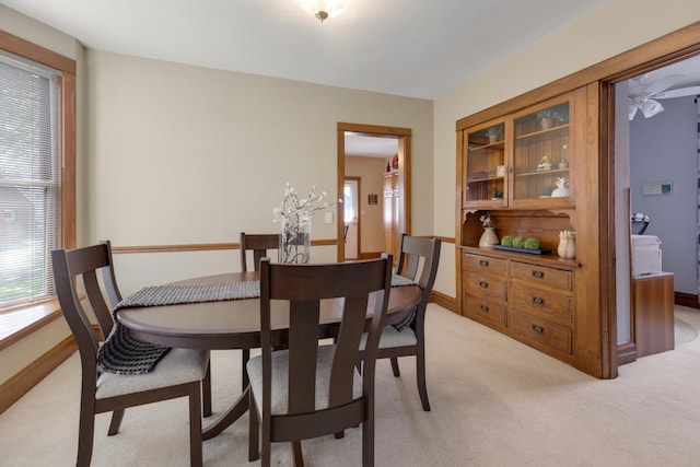 dining area featuring light colored carpet, healthy amount of natural light, and baseboards