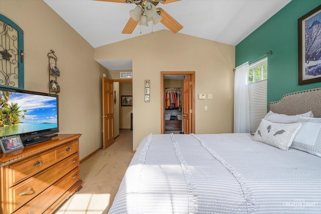 bedroom with vaulted ceiling, a walk in closet, light carpet, a closet, and ceiling fan