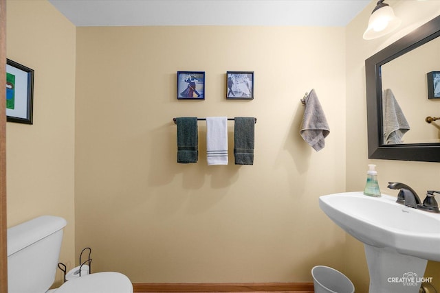 half bath featuring toilet and a sink