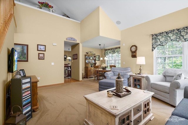 living room with light carpet, high vaulted ceiling, and baseboards