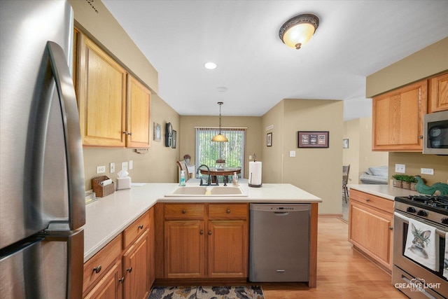 kitchen featuring stainless steel appliances, a sink, a peninsula, light countertops, and recessed lighting