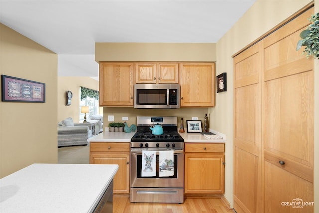 kitchen featuring appliances with stainless steel finishes, light countertops, light wood-style flooring, and light brown cabinetry
