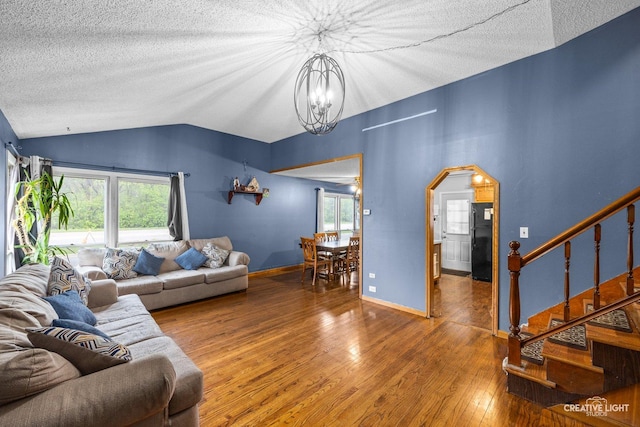 1020 Hahn Pl, West Chicago, IL 60185 - living room featuring vaulted ceiling, wood-type flooring, a chandelier, a textured ceiling, and arched walkways