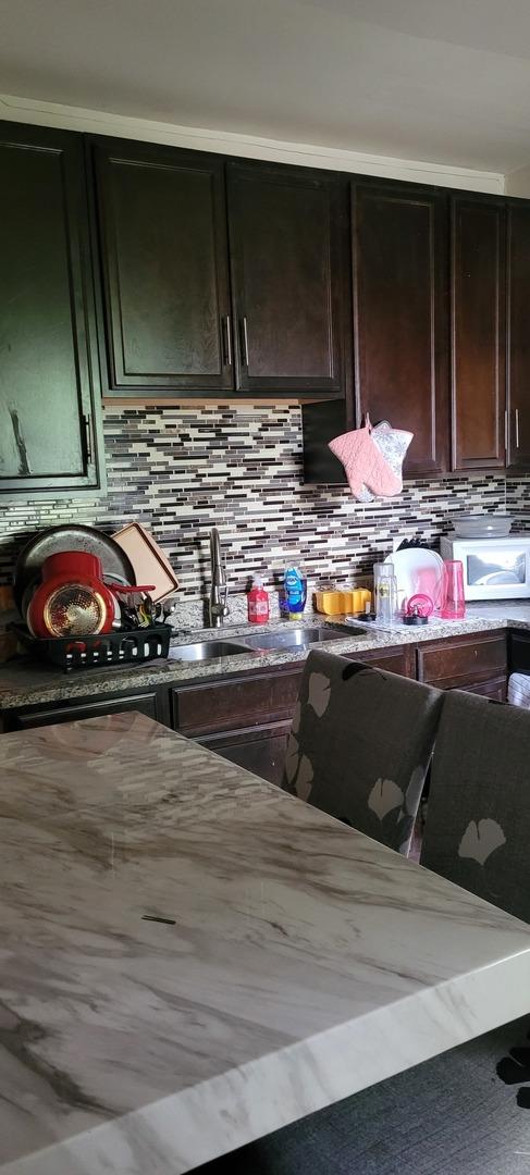 7542 S Peoria St, Chicago, IL 60620 - kitchen featuring backsplash, light stone counters, and a sink