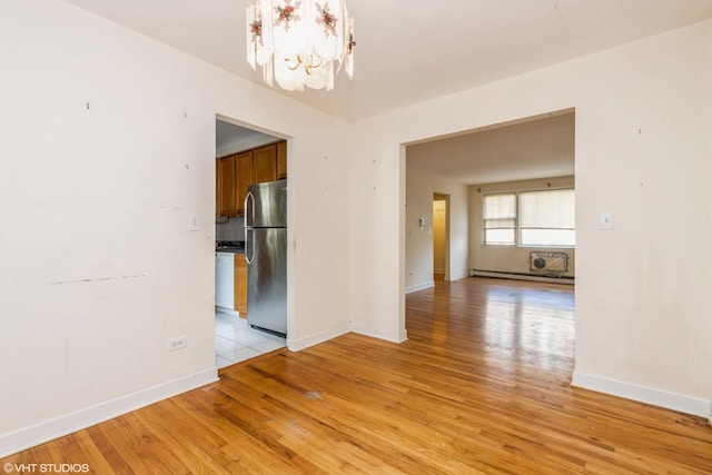 unfurnished dining area featuring a chandelier, light wood-style floors, and baseboards