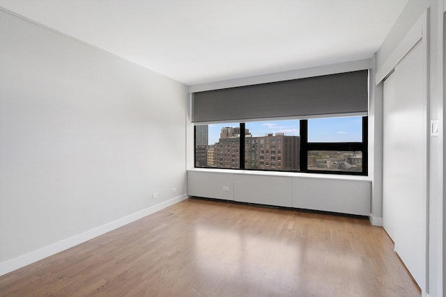 empty room featuring wood finished floors, baseboards, and a city view
