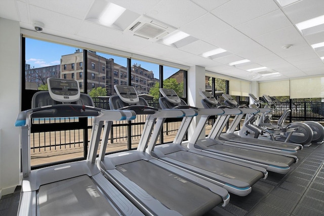 exercise room with a drop ceiling and a wall of windows