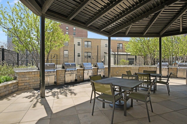 view of patio featuring exterior kitchen, area for grilling, outdoor dining area, and fence