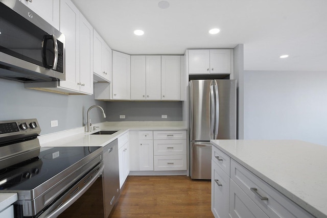 kitchen with stainless steel appliances, a sink, white cabinets, and recessed lighting