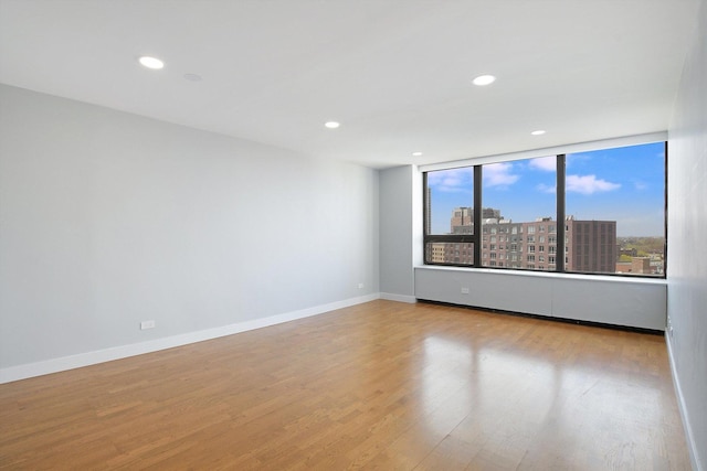 spare room featuring wood finished floors, baseboards, and recessed lighting