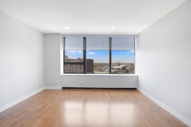 spare room with wood finished floors, baseboards, and recessed lighting