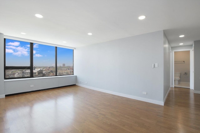 unfurnished room with wood finished floors, baseboards, and recessed lighting