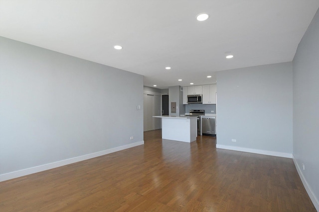 unfurnished living room featuring baseboards, dark wood-type flooring, and recessed lighting