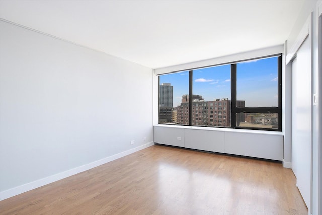 spare room with wood finished floors, baseboards, and a city view