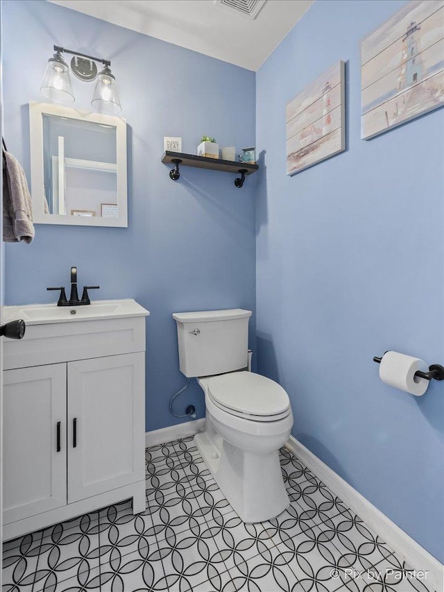 bathroom featuring baseboards, toilet, and vanity