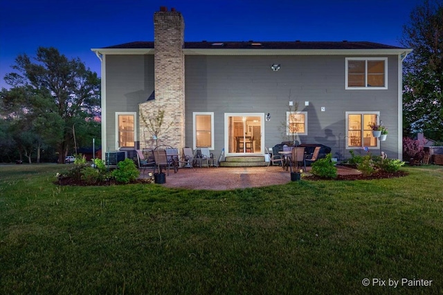 rear view of property featuring a patio, a lawn, a chimney, and entry steps