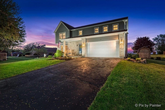 traditional home with asphalt driveway, a garage, a yard, and a porch