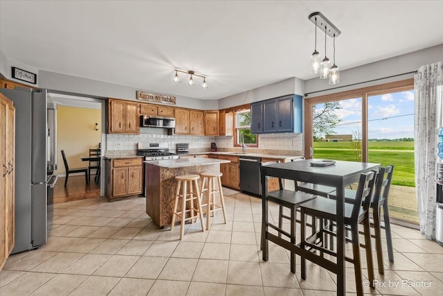 kitchen featuring stainless steel appliances, light tile patterned floors, decorative backsplash, a kitchen island, and light countertops