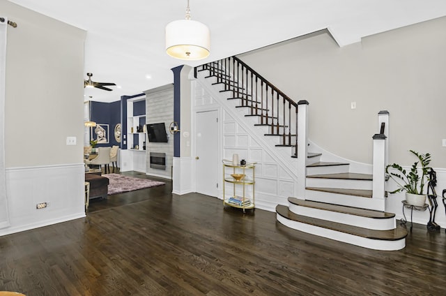 4738 S Champlain Ave, Chicago, IL 60615 - stairs with wood finished floors, wainscoting, a fireplace, a decorative wall, and a ceiling fan