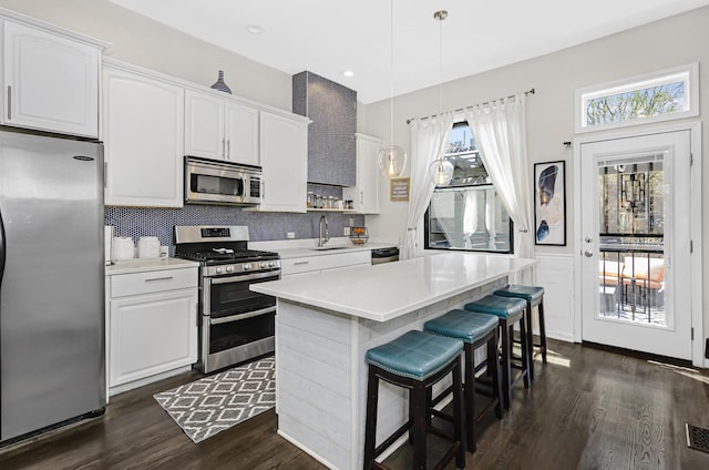 4738 S Champlain Ave, Chicago, IL 60615 - kitchen featuring stainless steel appliances, a sink, dark wood-style floors, a kitchen bar, and white cabinets