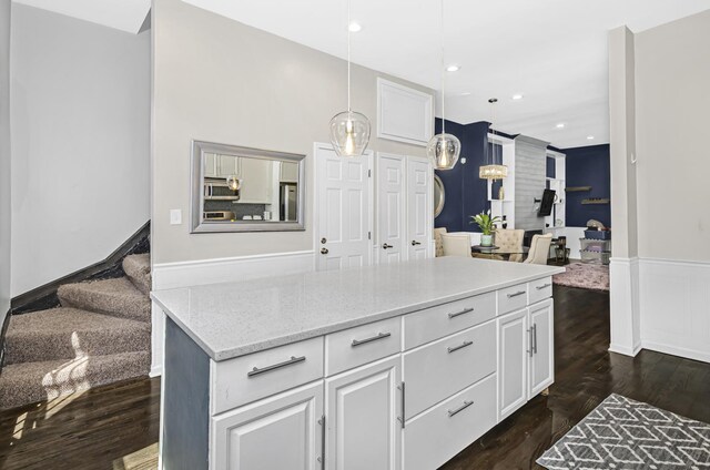 4738 S Champlain Ave, Chicago, IL 60615 - kitchen with stainless steel microwave, refrigerator, dark wood-style flooring, light stone counters, and a wainscoted wall
