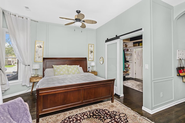 4738 S Champlain Ave, Chicago, IL 60615 - bedroom with a barn door, dark wood-style flooring, baseboards, and a ceiling fan