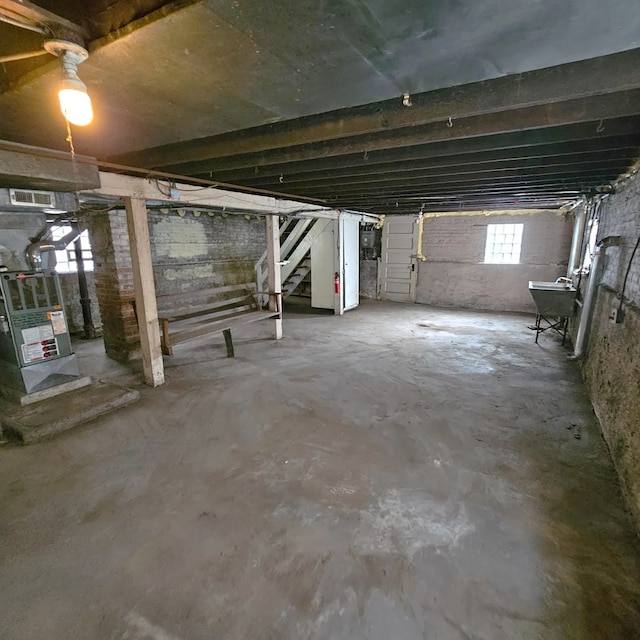 below grade area with stairs, heating unit, and a sink