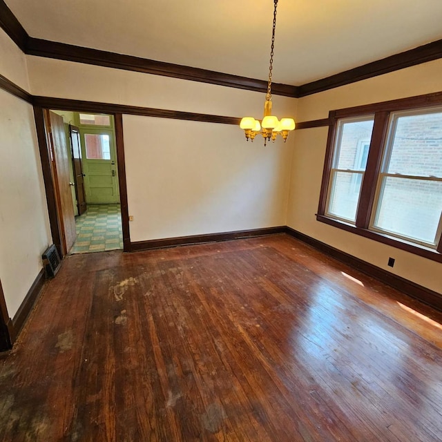spare room with hardwood / wood-style floors, a chandelier, ornamental molding, and baseboards