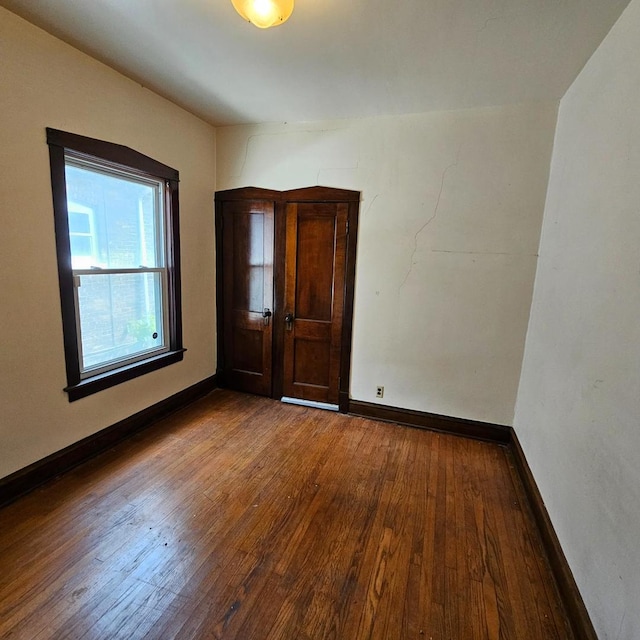 empty room with wood-type flooring and baseboards