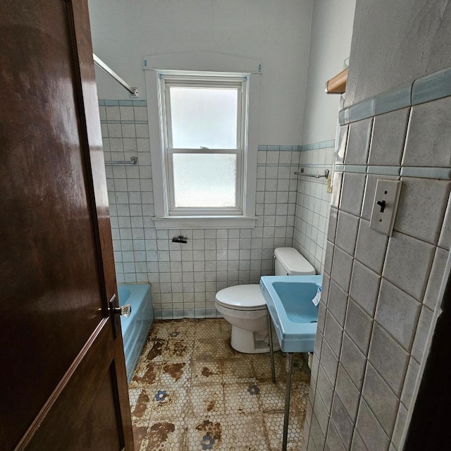 full bath with tile walls, tile patterned floors, toilet, and wainscoting