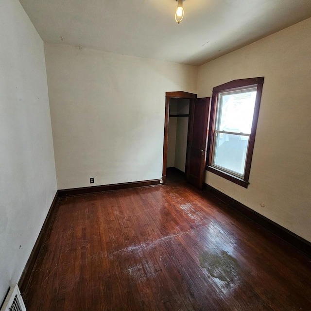 empty room with dark wood-style floors and baseboards