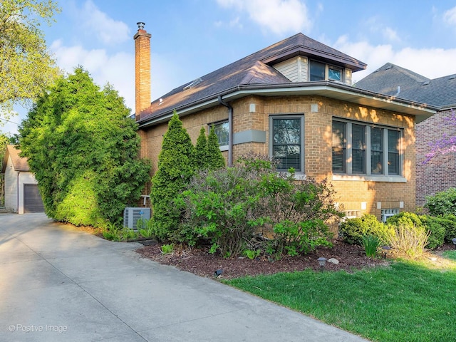 view of side of property with brick siding, a chimney, an outdoor structure, and central AC unit