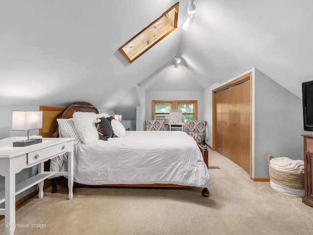carpeted bedroom featuring vaulted ceiling, a closet, a skylight, and baseboards