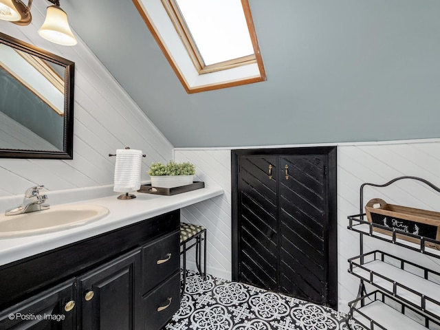 bathroom with a skylight, vanity, wood walls, vaulted ceiling, and tile patterned flooring