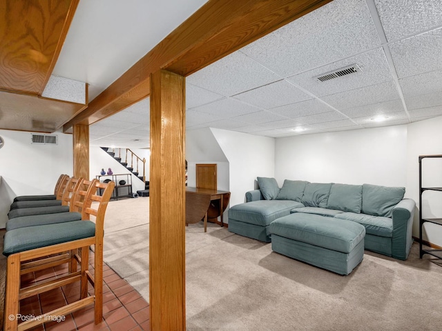carpeted living area featuring stairs, a paneled ceiling, and tile patterned flooring