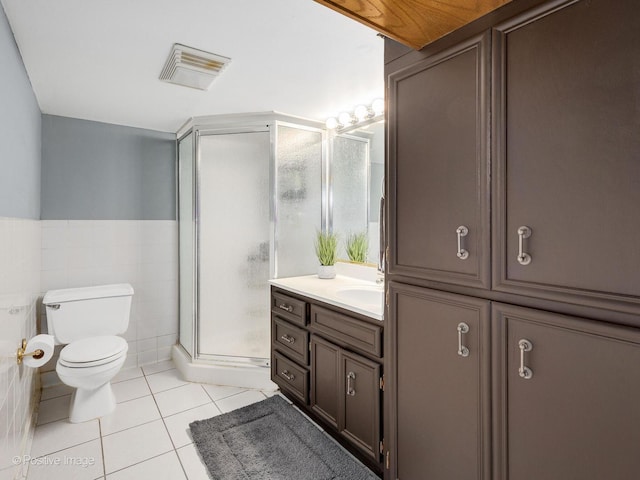 full bathroom featuring tile patterned flooring, a shower stall, toilet, vanity, and tile walls