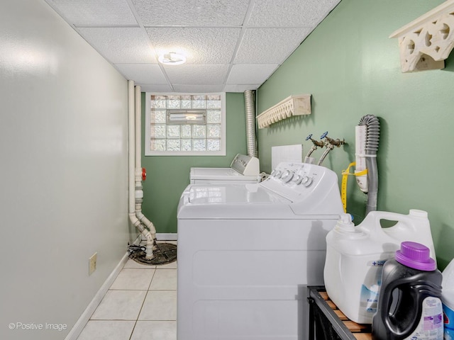 washroom with separate washer and dryer, light tile patterned floors, and baseboards
