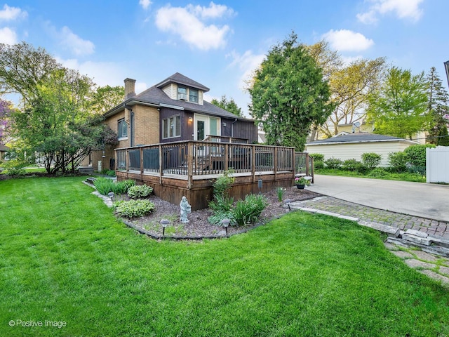 back of house featuring a deck, a chimney, a yard, and brick siding
