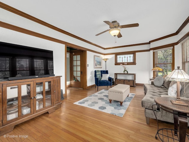living room with crown molding, light wood finished floors, ceiling fan, and baseboards