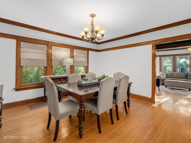 dining space featuring a chandelier, baseboards, light wood-type flooring, and ornamental molding