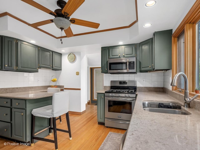 kitchen with stainless steel appliances, a sink, green cabinetry, tasteful backsplash, and recessed lighting