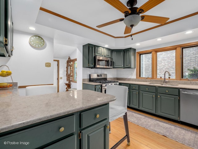 kitchen featuring appliances with stainless steel finishes, green cabinets, a sink, and recessed lighting