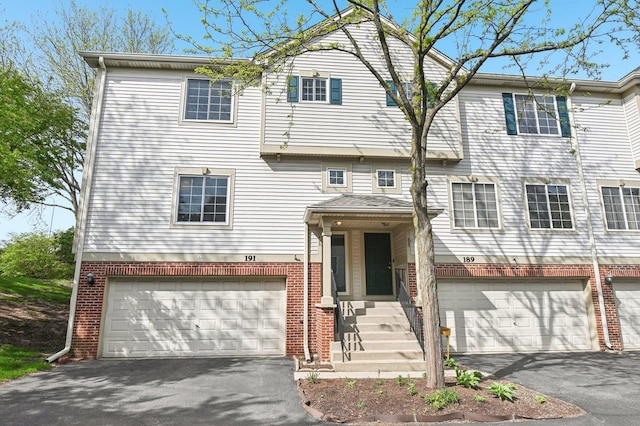 multi unit property with a garage, driveway, and brick siding